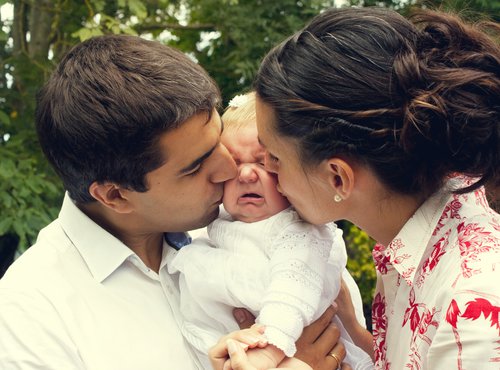Mom and Dad kissing baby